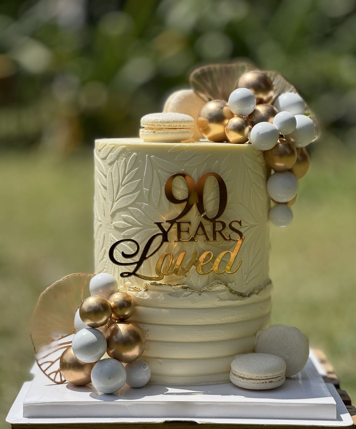 Ivory buttercream cake with gold and white sugar pearls, decorated for a 90th birthday