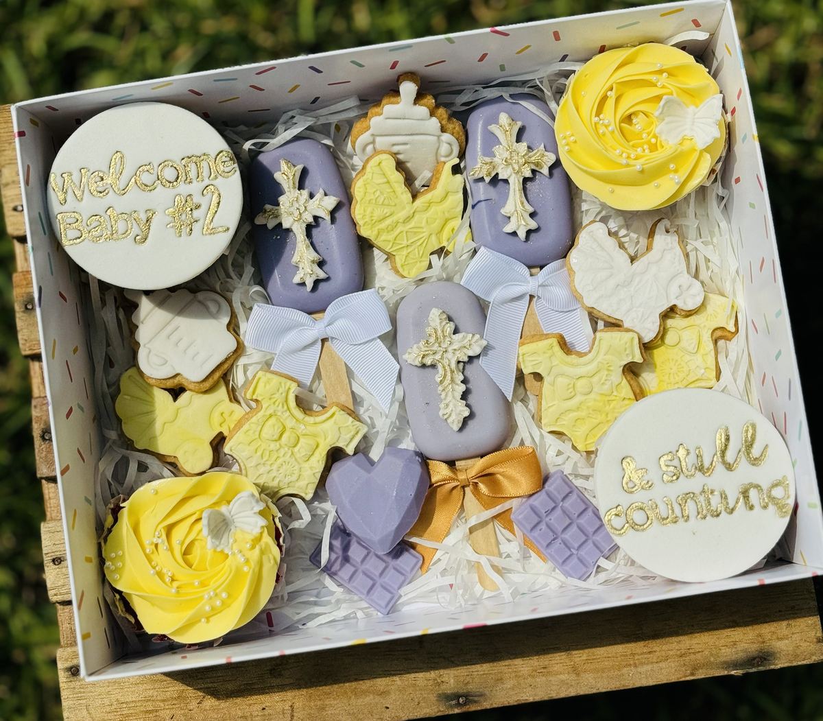 Gift box of lavender and yellow themed cookies and cupcakes welcoming a new baby