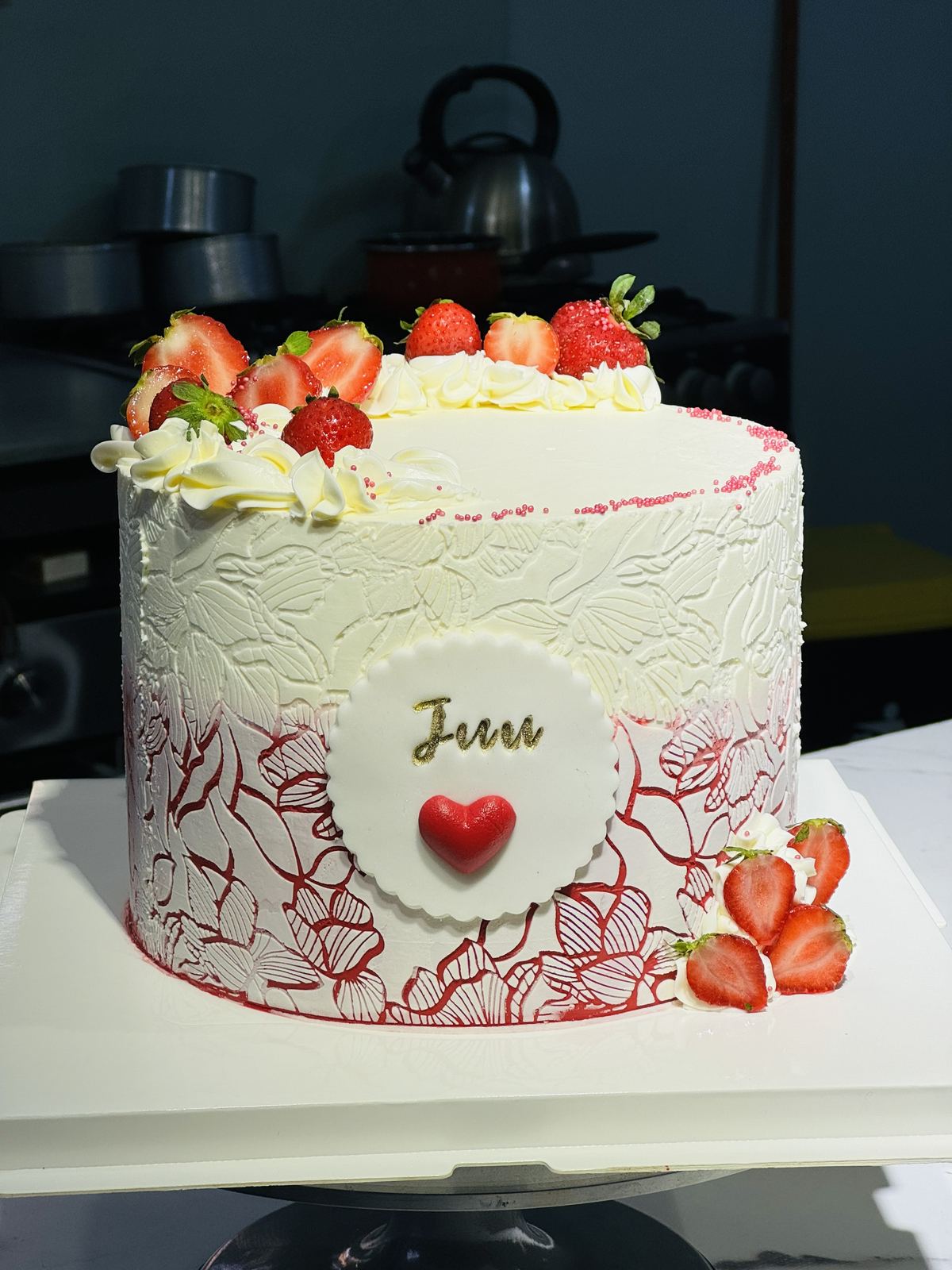 White buttercream cake with fresh strawberries and a red fondant heart